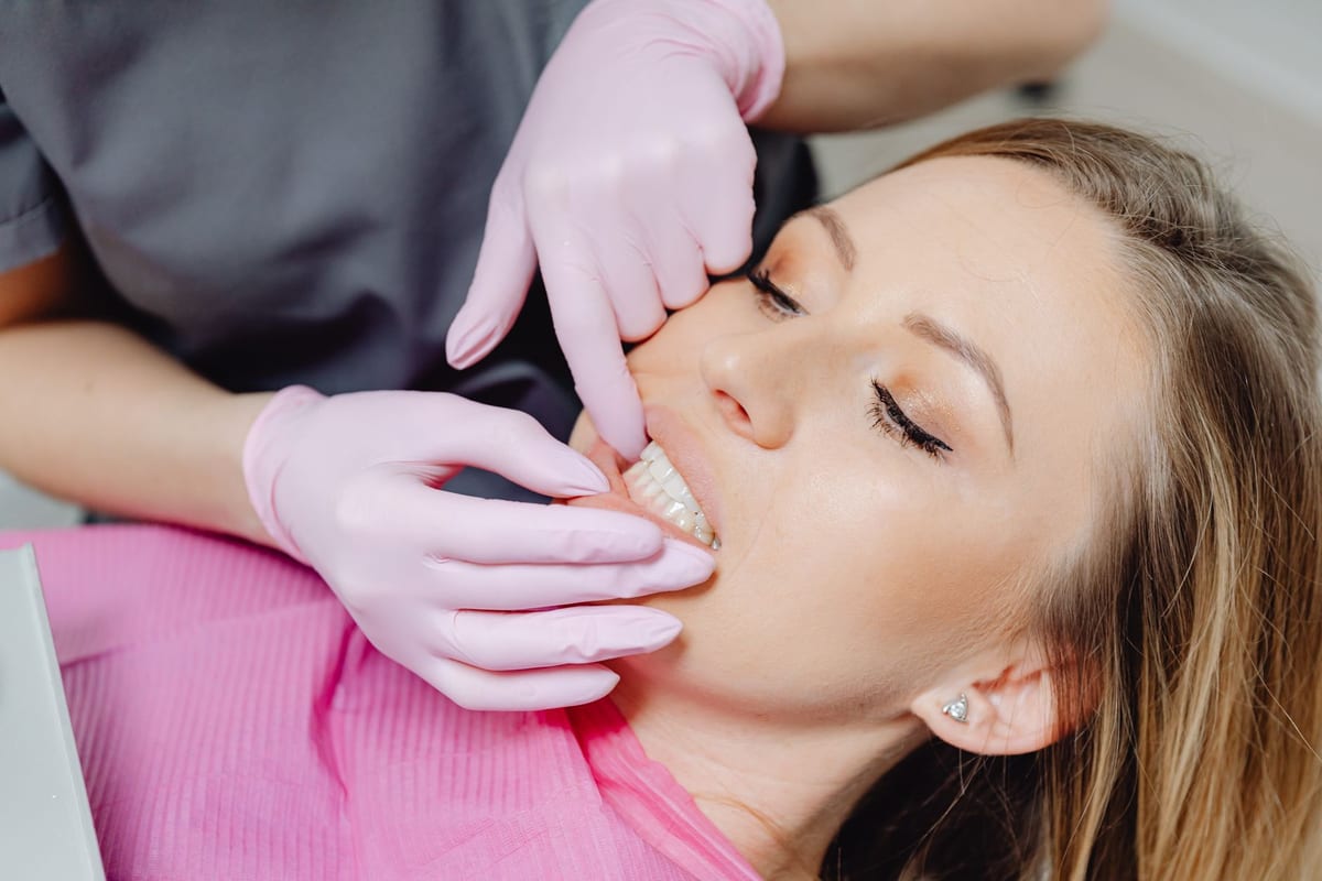 Gloved hands gently retracting a patient's lip to check the gum line